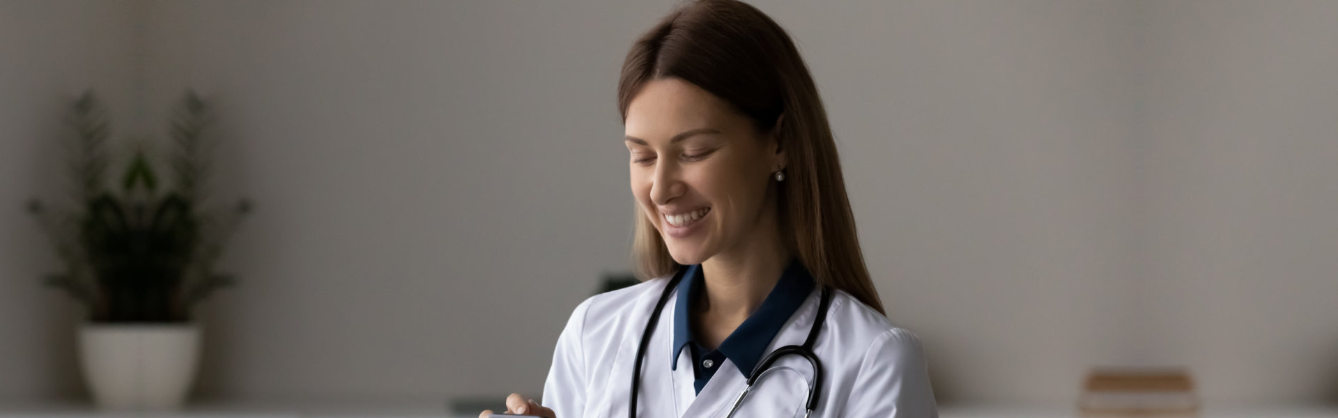 A female doctor smiling while holding a mobile device